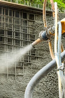Betonspritzmaschine bei der Anwendung von Spritzbeton auf Gitterstruktur, Bau der Hermann