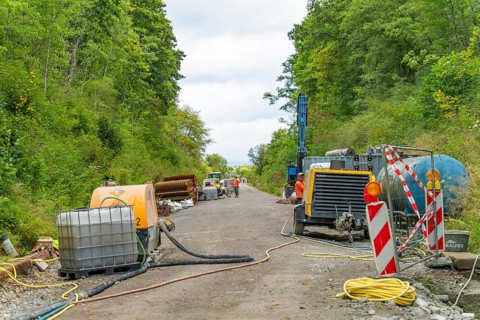 Baustellenszene mit Maschinen und Geräten entlang einer Straße in bewaldetem Gebiet, Bau der