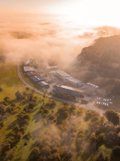 Nebel umhüllt Industriegebäude und Bäume in einer weichen Morgenlichtstimmung, Gechingen,