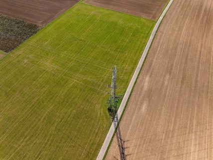 Hochspannungsmast auf einer weiten Feldlandschaft, eingefangen von oben, mit Schattenwurf, Nagold,