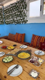 Rustic wooden table features a spread of moroccan breakfast food, with a pan of omelette,