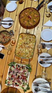 Table set for a dinner party with a large paella of shrimp, baked vegetable gratin and a vibrant