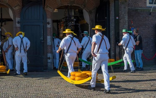 Männer in weißer Kleidung transportieren Käse auf einem Markt zur ehemaligen Stadtwaage,