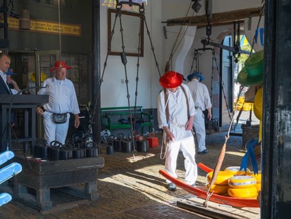 Männer in traditioneller Kleidung transportieren Käse in einem geschlossenen Raum, ehemalige