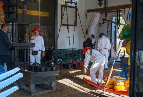 Männer mit roten Hüten bereiten Käse auf einem traditionellen Markt vor, ehemalige Stadtwaage, Käse