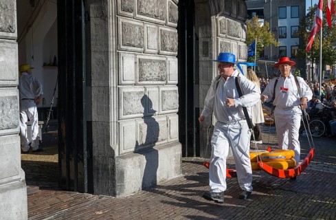 Männer mit blauen und roten Hüten bringen Käse auf den Markt zur ehemaligen Stadtwaage, Käseträger,