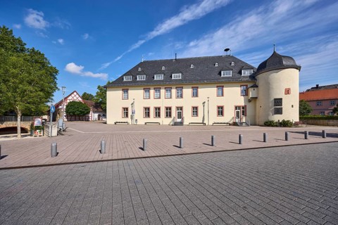 Kellereigebäude Hofheim, Bürgersteig, Absperrpoller, Bäume, Laterne, blauer Himmel, Cumuluswolken,