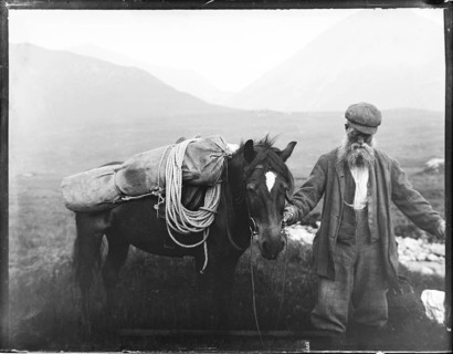 Old man with pack horse carrying mountaineering equipment, thought to be Cuillin mountains, Skye,