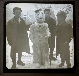 Magic lantern slide three boys making a snowman in a garden, England, UK c 1900-1910