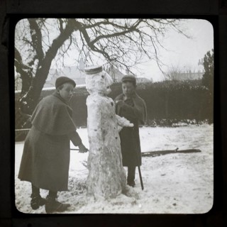 Magic lantern slide two boys making a snowman in a garden, England, UK c 1900-1910