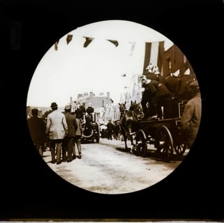 Horse drawn fire engines procession at a patriotic event with bunting flags across the street,