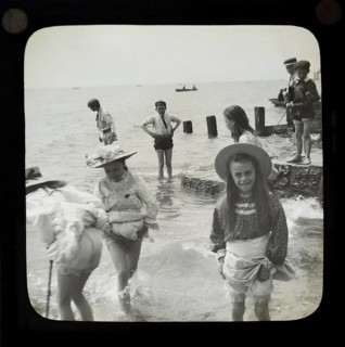 Magic lantern slide of children boys and girls paddling playing in the sea, UK circa 1900