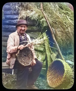 Portrait of elderly countryman weaving straw baskets in England, c 1890s-1900