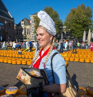 Smiling woman in traditional traditional costume carrying cheese at a busy market, cheese, cheese