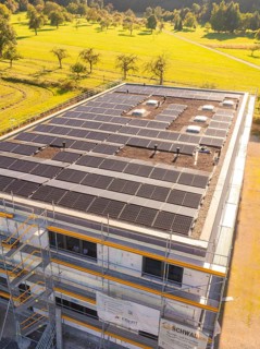 Close-up of a building with solar panels and scaffolding in green surroundings, new building with