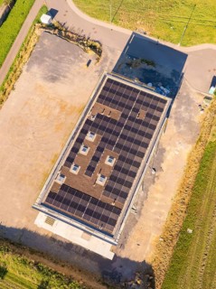 Top view of building with solar roof surrounded by an open area and fields, new building with green