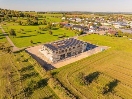 New building with solar panels, embedded in green fields, near a village, new building with green