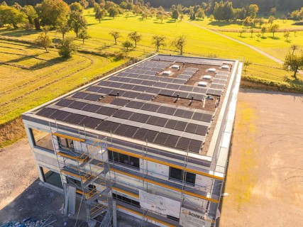 Building with solar panels and scaffolding in a green landscape, new building with green roof and