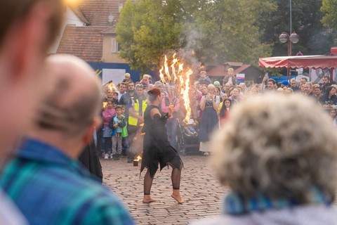 Dancer with burning torch, surrounded by an attentive audience at a street festival, Fire Night,