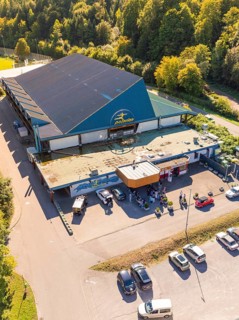 Close-up of an entrance area with car park, surrounded by forest, sunny surroundings, Polarion Ice