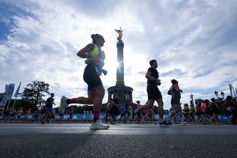 Runners run around the Victory Column against the backlight of the sun on the Great Star at the