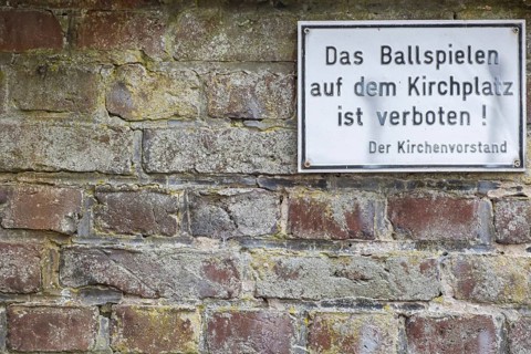 Sign with inscription Playing ball games on the church square is prohibited! The church council,