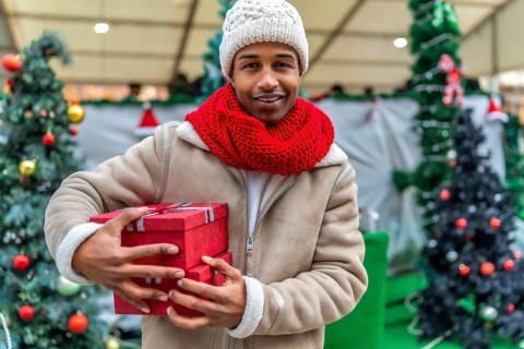 Happy young man holding colorful christmas gifts while enjoying the festive atmosphere of a