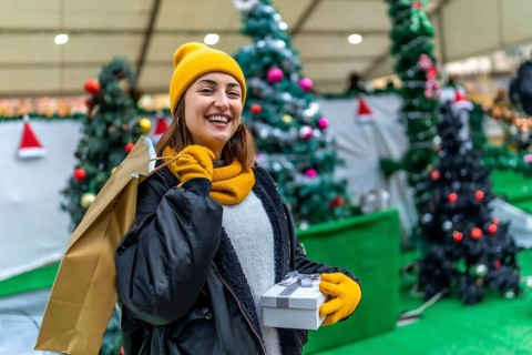 Smiling woman carrying shopping bags and gift box enjoying christmas shopping at a decorated
