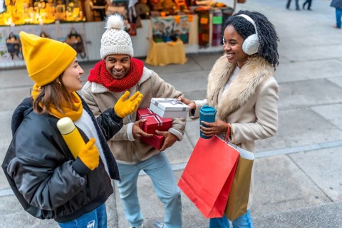 Happy multi ethnic friends exchanging christmas gifts and enjoying hot drinks at a winter christmas