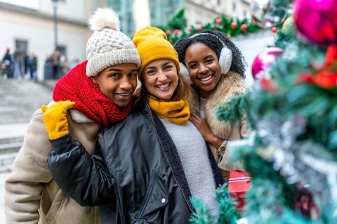 Happy multi ethnic friends enjoying christmas city during winter holidays, wearing winter clothes