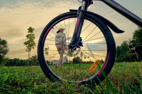 A woman enjoying a peaceful moment of sunset in nature while standing near her bicycle. She is