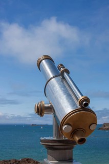 Binoculars point to the vast blue sea under a clear sunny sky, Saint Malo, Brittany, France