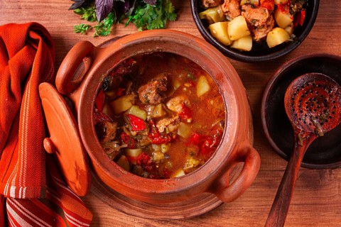 Chanakhi, a Georgian dish. in a clay pot, on a wooden table, stewed meat with vegetables, homemade,