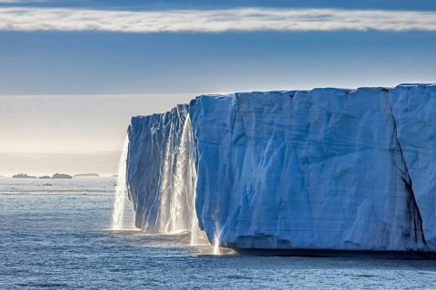 Waterfall at edge of Brasvellbreen glacier from the ice cap Austfonna pouring fresh water into the