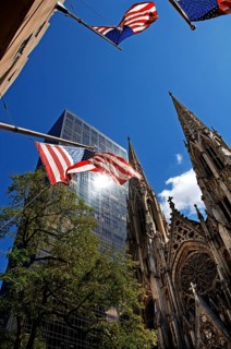 Towers of St Patrick's Cathedral in front of skyscrapers, waving US flags, New York City, USA