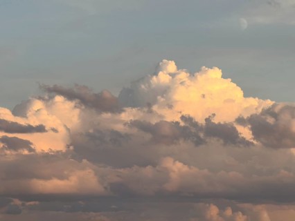 Mystical impression of cumulus cluster clouds at dusk illuminated by warm light, in the background