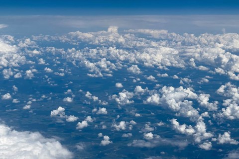 Aerial view from an aeroplane at high altitude of many white, bright cluster clouds Altocumulus,