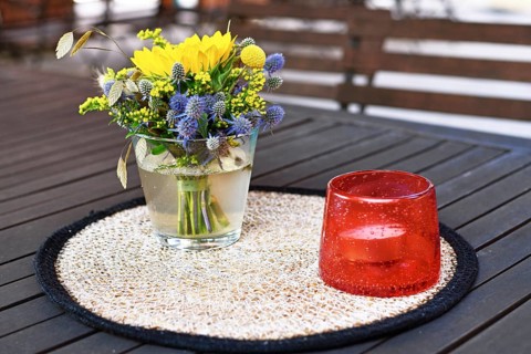 Close up of yellow and purple flower bouquet and storm lamp with candle decoration on table