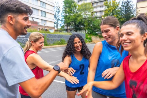 Mixed basketball team celebrating victory after match, putting their hands together, expressing joy