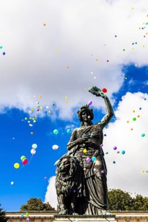 Colourful balloons rise high above the statue of Bavaria into the white-blue sky, grand finale of