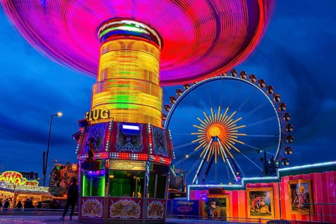 Illuminated chain carousel in motion, behind the Ferris wheel at standstill, Festwiese,