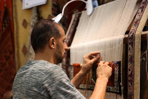 A Syrian weaver showcases the craft of traditional textile-making inside the Damascus International