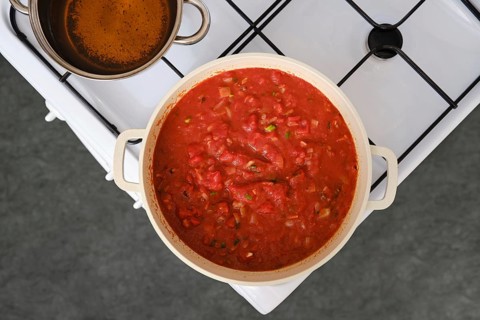 Overhead view of cooking tomato and bread soup on a stove