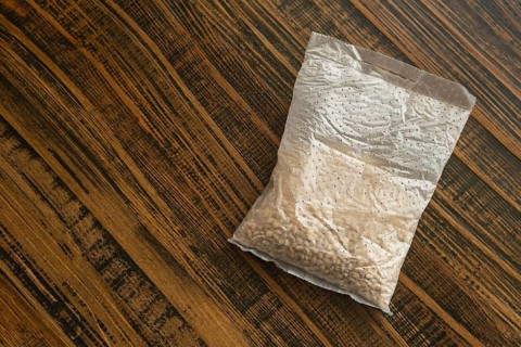 A sachet containing pearl barley is placed on a wooden kitchen table. It is ready for cooking,