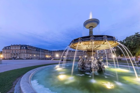 Evening atmosphere at Schlossplatz Stuttgart. View of the New Palace. Illuminated fountain bowl at