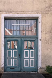 Blue wooden door with windows and white curtains on a rustic building, Old Town Burgsteinfurt,
