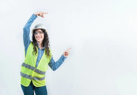 Smiling female builder pointing an advertisement isolated. Beautiful female engineer pointing to