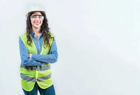 Portrait of smiling female engineer with arms crossed isolated. Young female engineer with helmet