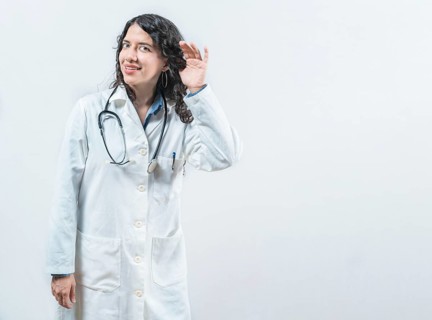 Latin female doctor listening to gossip, looking at camera. Doctor with hand on ear listening to