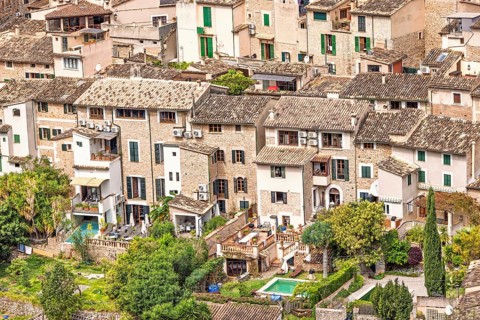 View at old idyllic residential houses with lush green gardens on an old village from an aerial